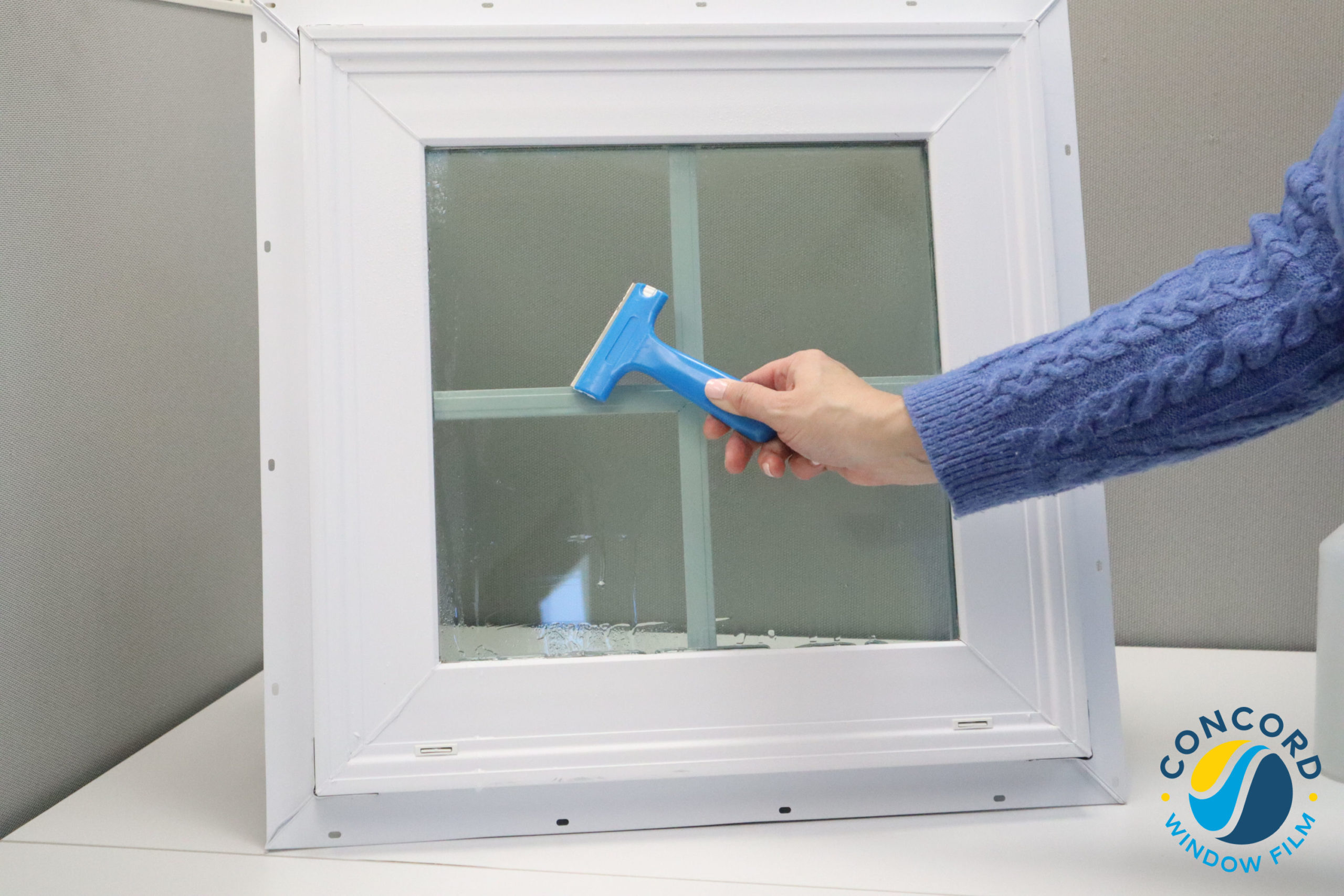 Using a razor blade scraper to remove window film adhesive