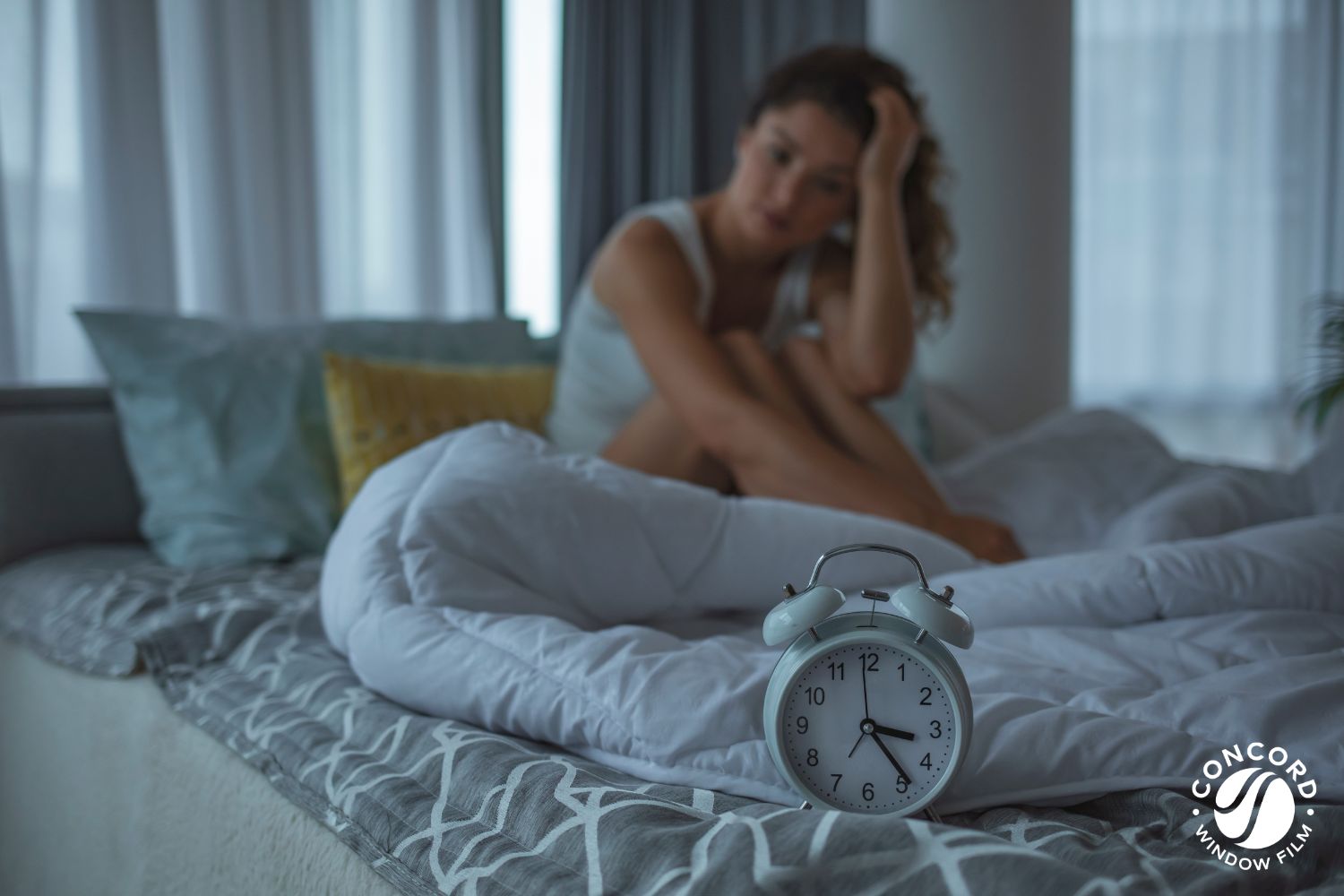Woman who can't sleep awake in bed with an alarm clock that shows 3:30 AM for a blog post on good sleep hygiene