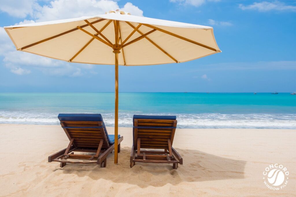 Two chairs on the beach under an umbrella for a post on UV blocking window film for eye health