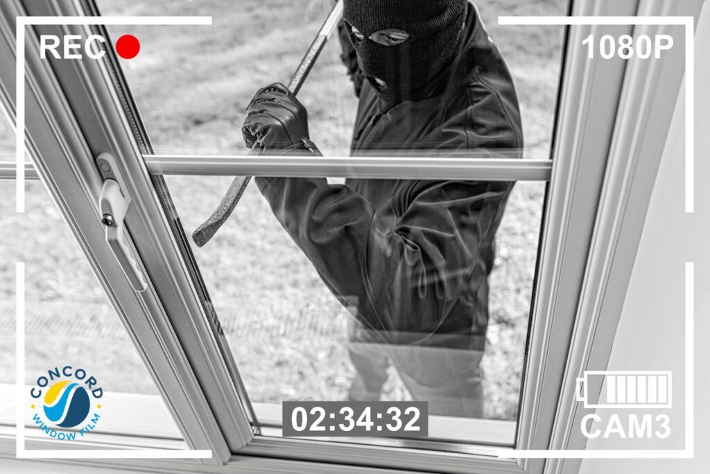 Photo of a burglar getting ready to break a window to gain entry into a home for a post on safety window film