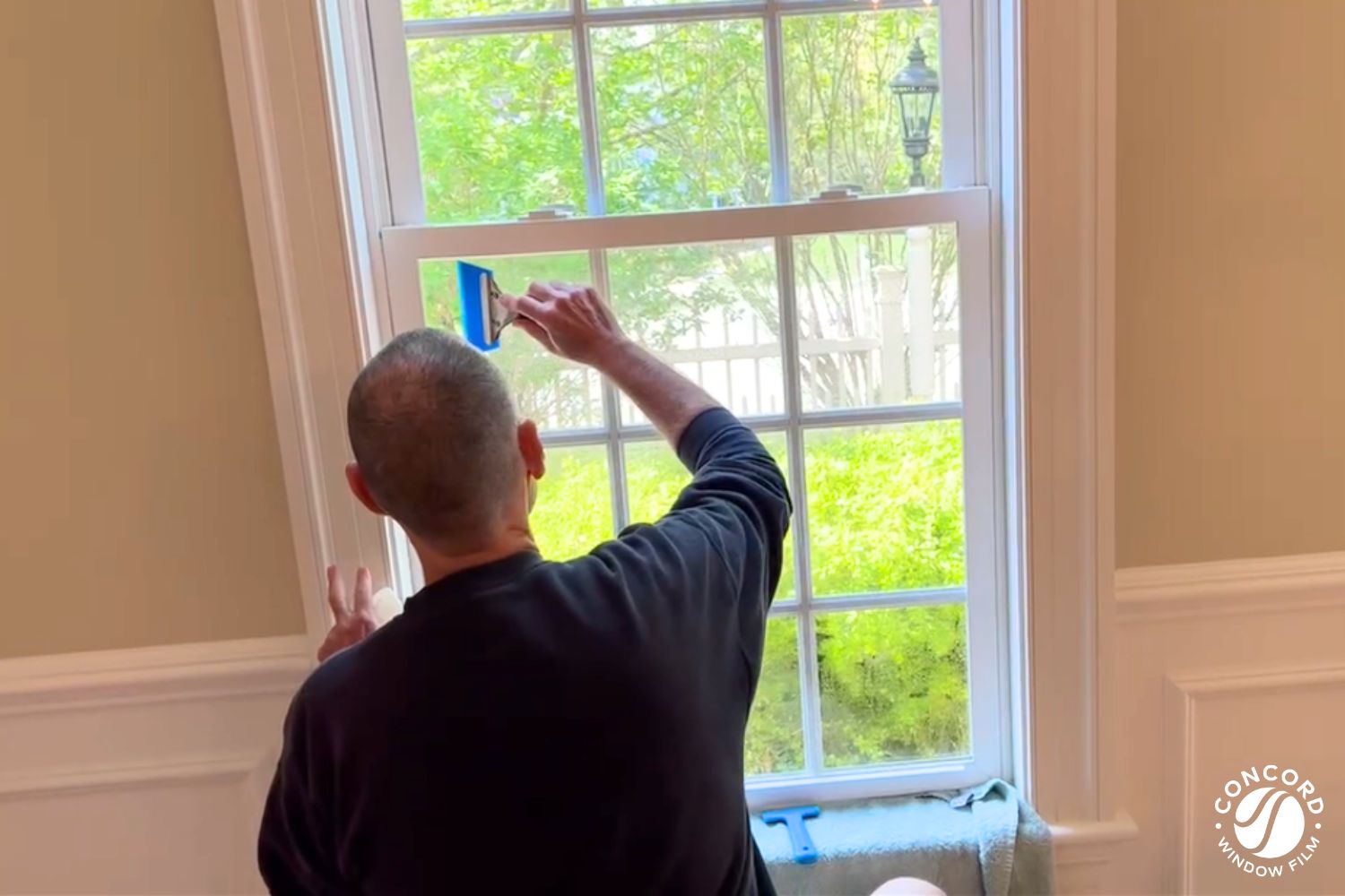 Man installing ComforTech Window Film on a double hung window for a post on what makes ComforTech Ceramic Series Window Film the best choice for homeowners.