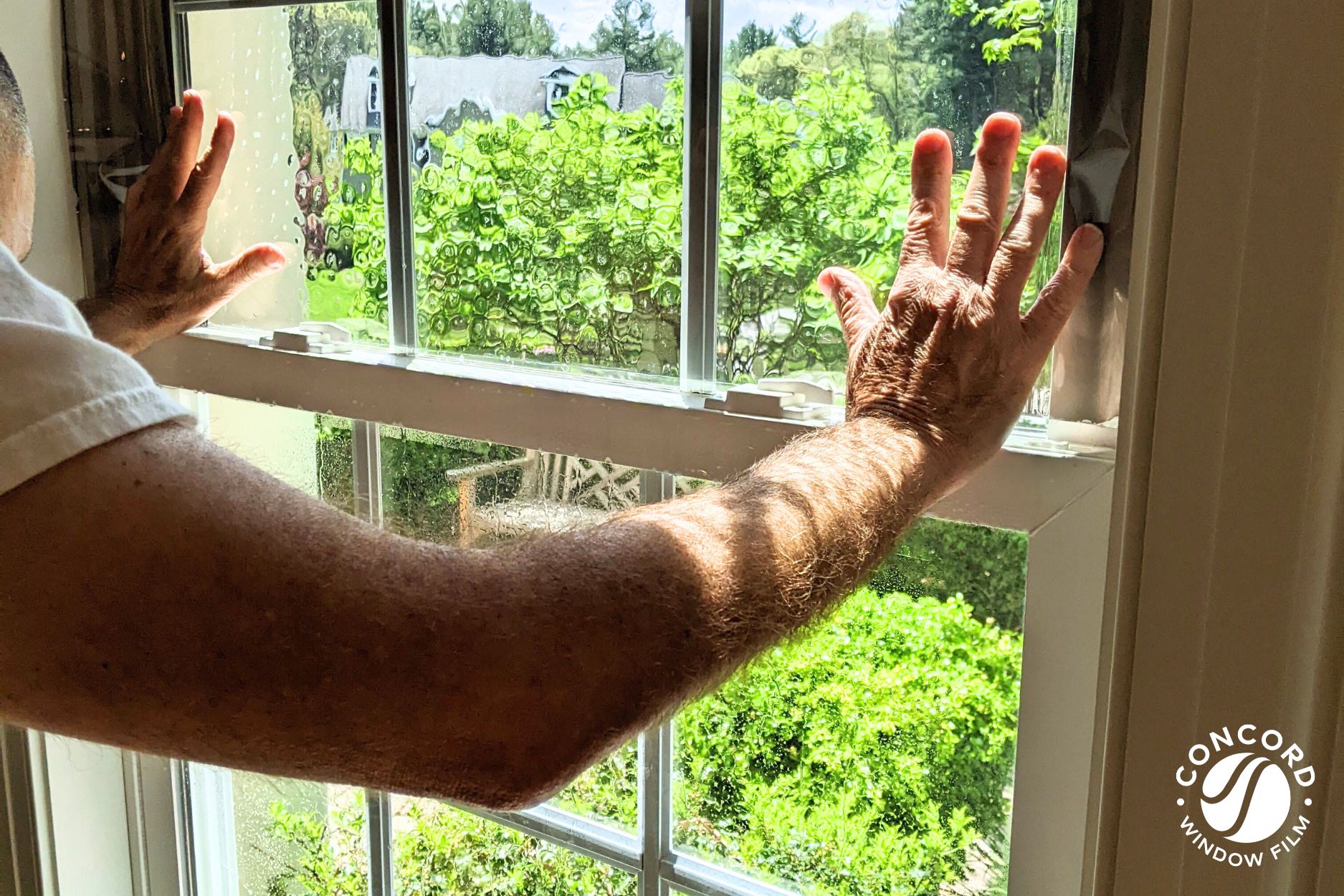 A photo of a man installing ComforTech Ceramic Series window film on a double pane window for a post entitled Common window film installation questions